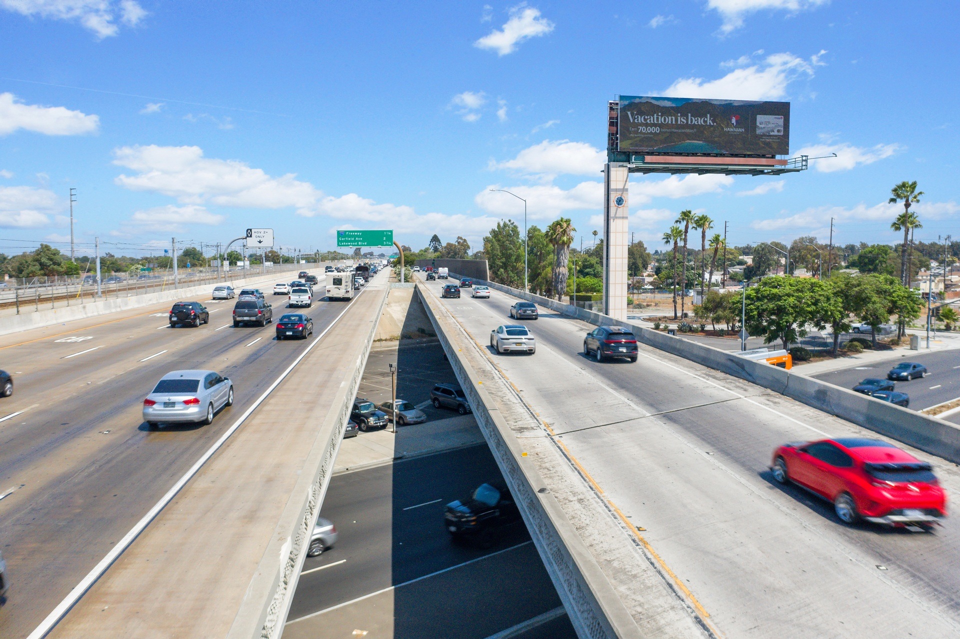 Multi-lane freeway with billboard under blue sky