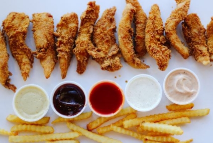 Plate of fried chicken tenders, fries, and dipping sauces.