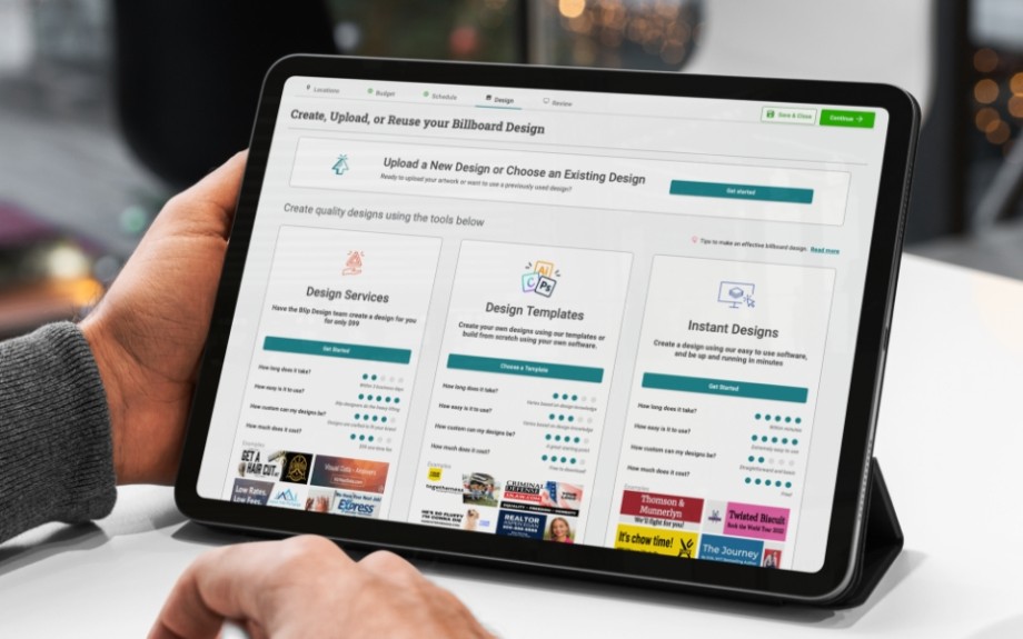 Person using a tablet to design and upload billboard ads on Blip's self-serve platform showing design service options.
